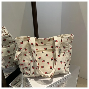 Close-up of strawberry print corduroy tote bag featuring a front zipper pocket