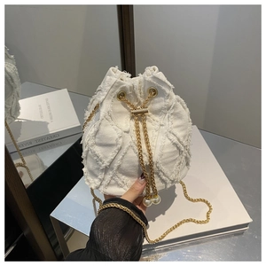 Detail der weißen Denim-Beuteltasche mit ausgefranstem Rautenmuster und Perlenkette