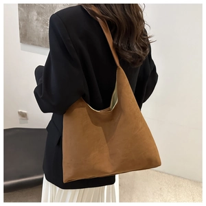 Back view of a model wearing a large brown suede shoulder bag with a black blazer