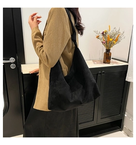 Grand sac fourre-tout en daim noir porté avec un blazer pour un style moderne et décontracté