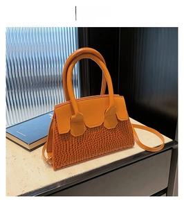 Dettaglio della borsa a tracolla in pelle giallo-marrone con texture mista e manici