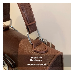 Detail of silver hardware and stitching on a brown litchi texture handbag handle
