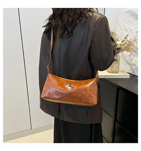 Brown vintage faux leather crossbody bag with silver star ornament worn by a model