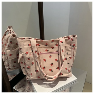 Detail of pink corduroy tote bag featuring strawberry pattern and functional zip pocket