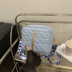 Sac bandoulière matelassé bleu clair avec boucle à pompon dorée et sangle large