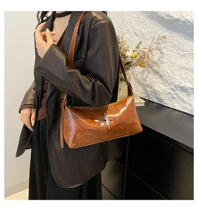 Detail of vintage brown leather underarm bag with a silver star buckle on a woman's shoulder