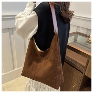 Brown suede shoulder bag on model showing large capacity and minimalist hobo style