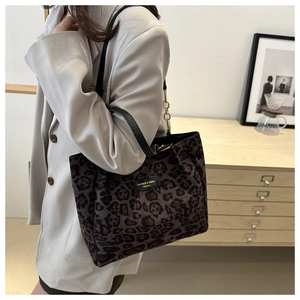 Detailed view of leopard print tote bag with black strap worn by a model in a beige suit
