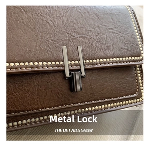 Macro detail of brown leather bag with contrast stitching and gunmetal clasp lock