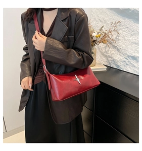 Detail of red vintage leather shoulder bag with silver star metal hardware and adjustable strap