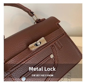 Close-up of silver metal twist lock and lychee pattern leather flap on brown handbag