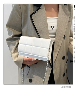 Detailed view of a white quilted leather shoulder bag with a woven silver chain strap