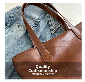 Close-up of pebble grain leather tote bag with geometric stitching and wide strap