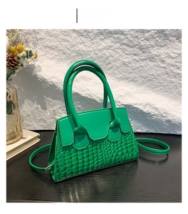Dettaglio della texture a coccodrillo verde e dei manici su una borsa a tracolla elegante