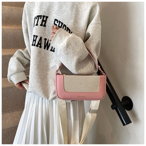 Dettaglio cuciture in pelle rosa e tela beige su una piccola borsa a tracolla rettangolare