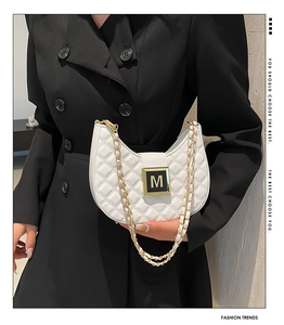 Detail of white quilted half-moon bag with gold M-buckle and metal chain strap