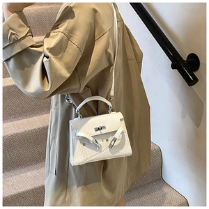 Side view of white lychee leather handbag with metal turn-lock on a model