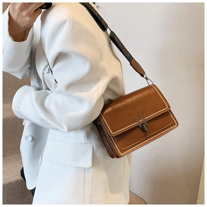 Dettaglio borsa a tracolla marrone vintage con borchie dorate e tracolla jacquard