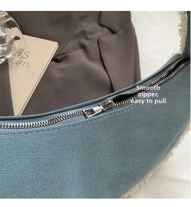 Detail of blue canvas hobo bag featuring white faux fur trim and silver zipper