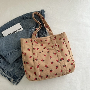 Corduroy tote bag with strawberry print and front pocket on a white fabric background