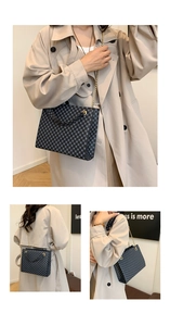 Detail of dark blue geometric pattern handbag with gold metal handle and chain strap
