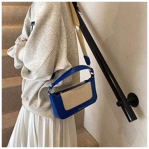 Dettaglio della borsa a tracolla bicolore con finiture in pelle blu e trama beige