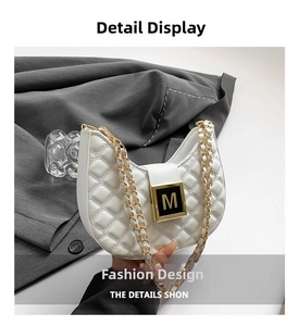Close-up of white quilted handbag featuring gold M buckle and woven chain strap