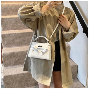 Close-up of white lychee pattern leather handbag with metal turn-lock on stairs