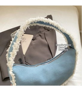 Detail of denim canvas crescent bag with plush white faux fur trim and metal zipper