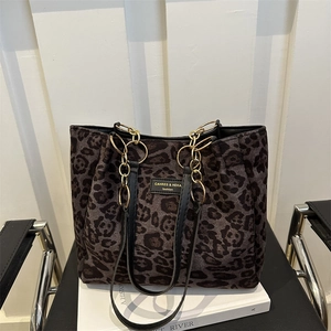 Leopard print tote bag with gold chain strap and black leather handle on a desk