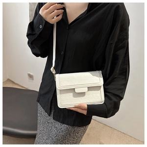 Detailansicht der weißen quadratischen Tasche mit Krokodilmuster und schmalem Gurt