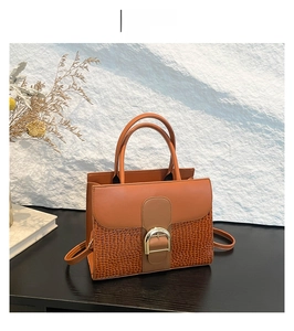 Detailed view of brown handbag showing smooth leather and crocodile texture with D-buckle