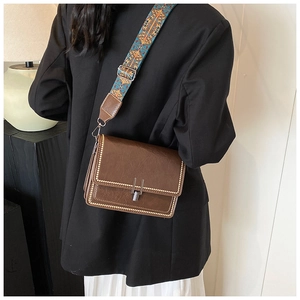 Close-up of brown vintage crossbody bag with jacquard strap and decorative stitching