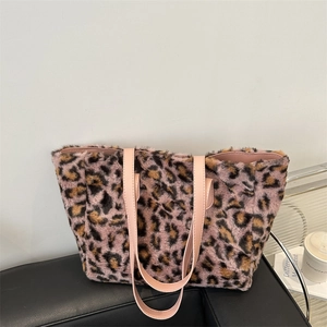 Chic leopard print plush tote bag with pink leather handles on a black sofa