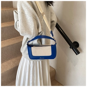 Dettaglio borsa a tracolla bicolore in pelle blu e tela con logo dorato centrale