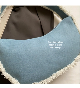 Detailed close-up of light blue canvas shoulder bag with soft white faux fur trim texture