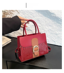 Detail of red and brown contrast leather handbag with crocodile pattern and golden U-buckle