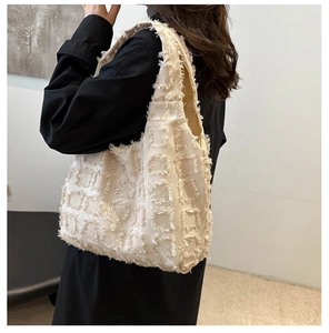 Détail du sac fourre-tout beige matelassé avec pompons sur un mannequin en robe noire