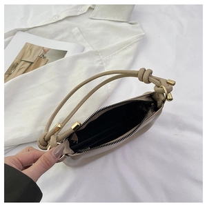 Detail view of beige saddle bag with knotted strap and gold hardware on fashion magazine
