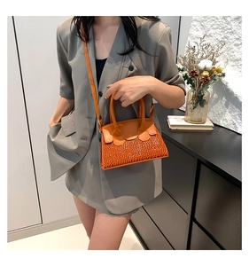 Dettaglio borsa a tracolla arancione con base strutturata ed elegante manico in pelle