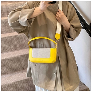 Dettaglio della borsa patchwork in pelle gialla e tela con tracolla larga indossata da modella