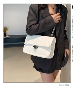 Detail of silver chain strap and shiny pleated leather texture on white shoulder bag