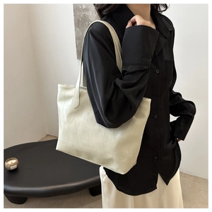 Detail of cream tote bag featuring unique geometric patchwork and thin shoulder strap