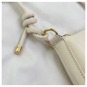 Close-up of cream white leather shoulder bag with knotted strap and gold hardware