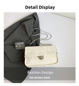 Detail of creamy white pleated handbag featuring a silver semi-circular lock and chain strap