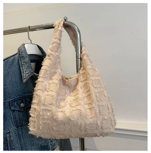Detail of the woven texture and fringe accents on the beige large capacity tote bag