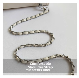 Detail of cream leather interwoven with silver metal chain strap and spring hook