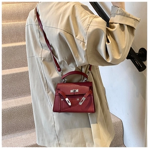 Detail of burgundy pebbled leather handbag with metallic twist lock and crossbody strap