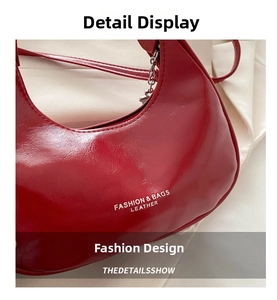 Detail of red crescent shoulder bag with glossy oil-wax leather texture and silver chain