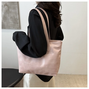 Pink tote bag with geometric textured detail shown on shoulder in minimalist setting